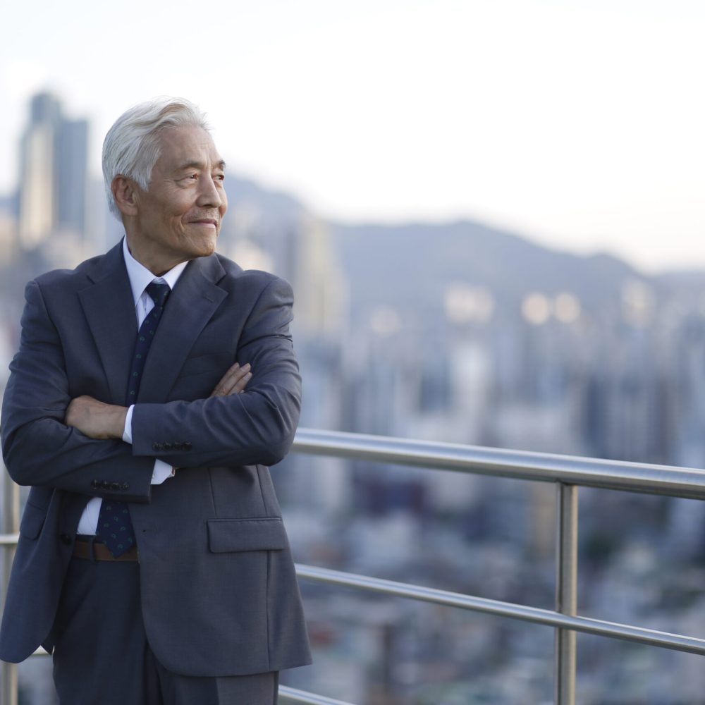 Senior businessman standing with arms crossed on rooftop