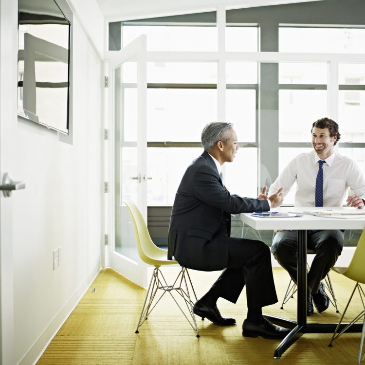 Coworkers discussing project in office conference room smiling